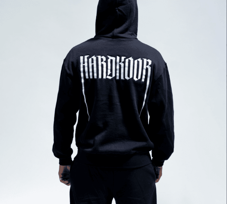 Achterkant van de hoodie van de burn-outfit met het Hardkoor logo groot in het wit op de zwarte trui